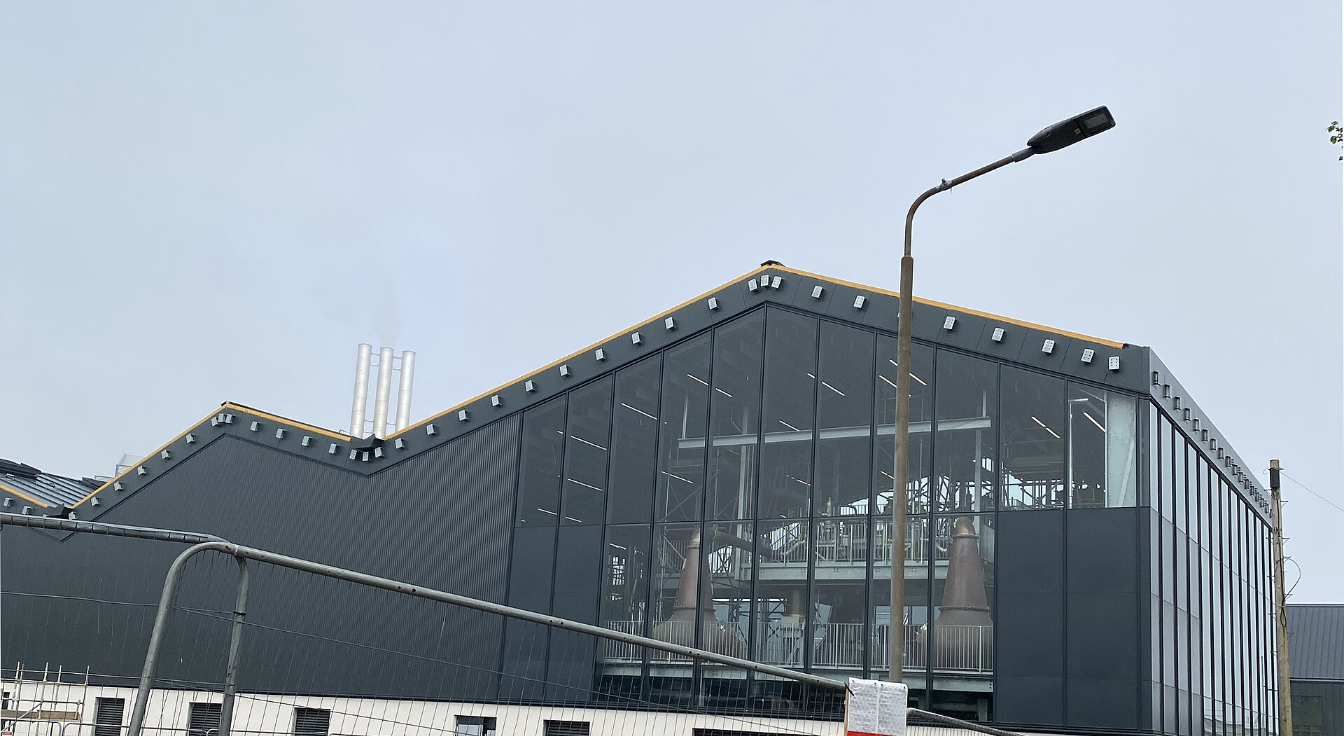 The rebuilt Port Ellen distillery mid-construction, 2023: the new copper stills visible through the still house glazing ahead of the March 2024 reopening.